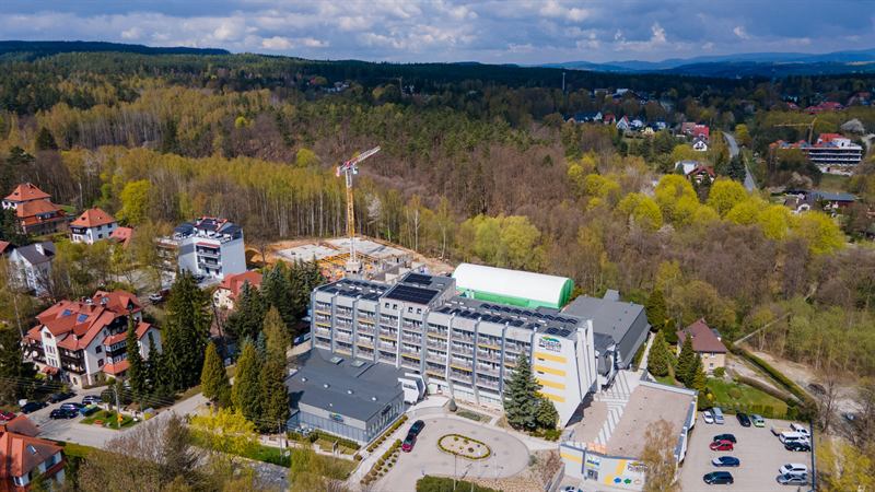 Letecký snímek staveniště aparthotelu obklopeného lesem